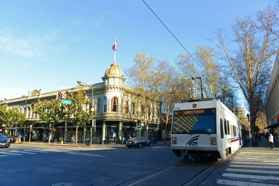 White VTA light rail train passing by historic building in downtown San Jose, California